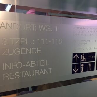 Hinweisschild eines ICEs mit Informationen in Großschrift, Punktschrift und mit Piktogrammen