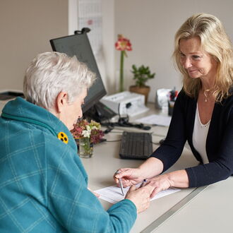 Britta Block, Sozialberaterin im BSVH, mit einer Ratsuchenden am Schreibtisch. Sie gehen gemeinsam Unterlagen durch.