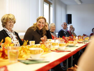 Die Seniorenberaterin des BSVH, Franziska Diesmann eingerahmt von Teilnehmern und Teilnehmerinnen ihres Seniorennachmittags. Alle sitzen an einem langen gedeckten Kaffeetisch.