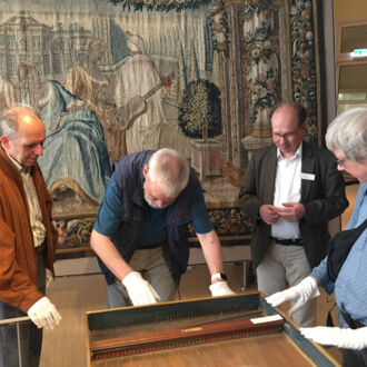 Eine Gruppe von Menschen mit Seheinschränkung betastet mit Schutzhandschuhen ein historisches Instrument im Museum für Kunst und Gewerbe. Die Begehung fand im Ramen des Sehbehindertentags 2018 statt.