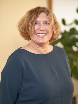 Wiebke Larbie hat honigblondes, welliges Haar, das sie zu einem Bob trägt. Sie lächelt strahelnd in die Kamera. Gekleidet ist sie mit einem dunkelgrünen Kleid.