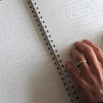Hände auf einem Punktschriftbuch beim Lesen. Bild: DBSV_Lautenschläger