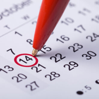 Ein Terminkalender, bei dem gerade mit einem roten Stift ein Datum markiert wird.