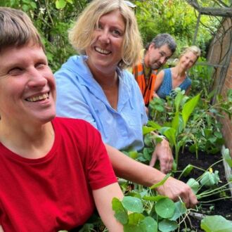 Vier unserer hauptamtlichen Mitarbeiterinnen und Mitarbeiter beim gemeinsamen freudigen Gärtnern an den Beeten im vereinseigenen Garten