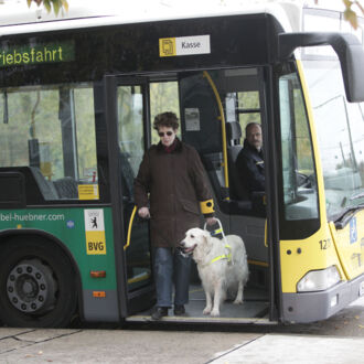Eine Frau mit Führhund steigt aus einem Linienbus aus