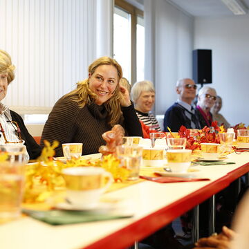 Die Seniorenberaterin des BSVH, Franziska Diesmann eingerahmt von Teilnehmern und Teilnehmerinnen ihres Seniorennachmittags. Alle sitzen an einem langen gedeckten Kaffeetisch.