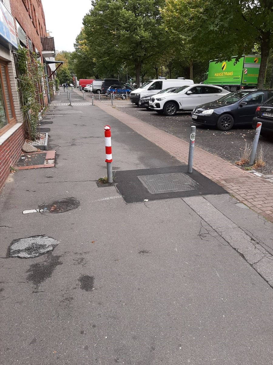 Grauer Straßenpoller in Eilbek mit rot-weiß-gesteifter Strichmütze