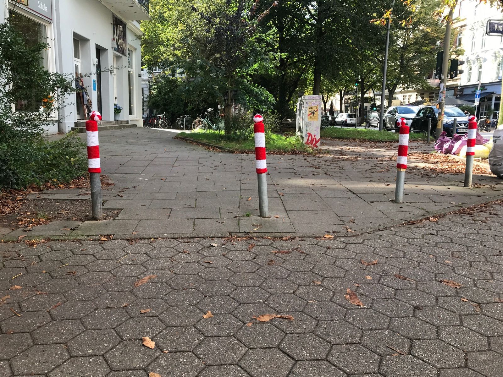 Graue Straßenpoller in Eimsbüttel mit rot-weiß-gesteiften Strichmützen
