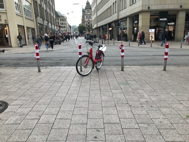 Graue Straßenpoller in der Innenstadt mit rot-weiß-gestreiften Strickmützen