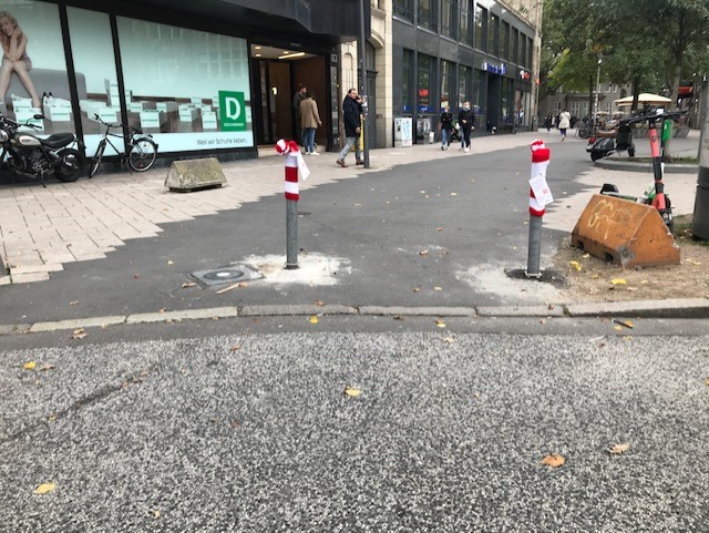 Graue Straßenpoller in der Innenstadt mit rot-weiß-gestreiften Strickmützen