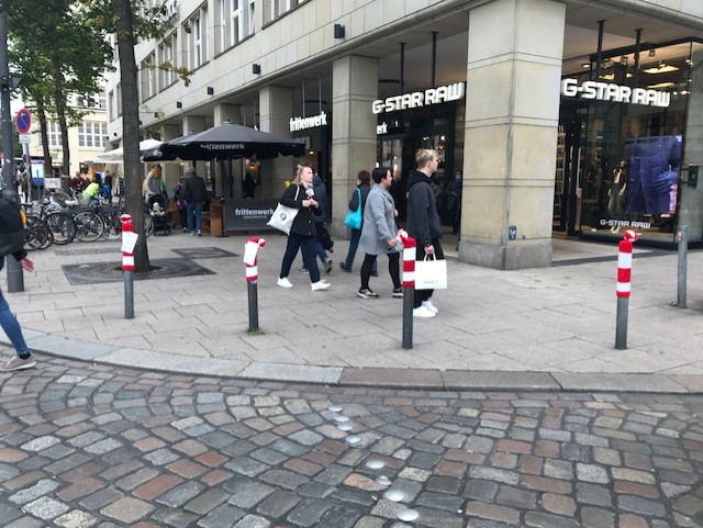 Graue Straßenpoller in der Innenstadt mit rot-weiß-gestreiften Strickmützen