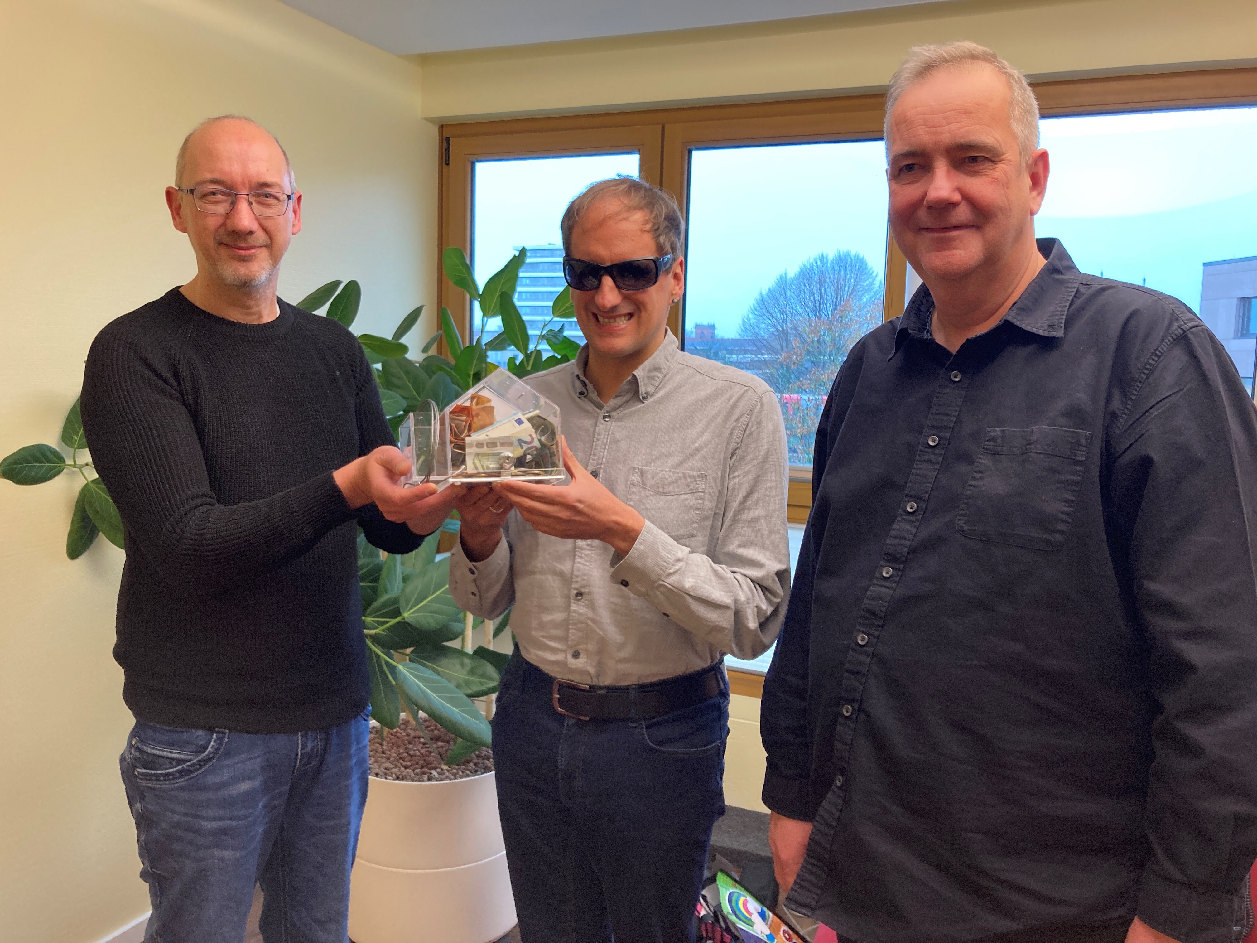 René (li.) und Sven Nitschke überreichen Heiko Kunert (mi.) ein volles Spendenhaus